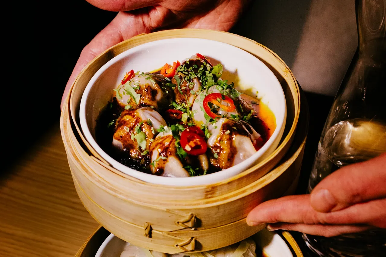 Dampede dumplings i bambuskurv, toppet med vårløk og fersk chili