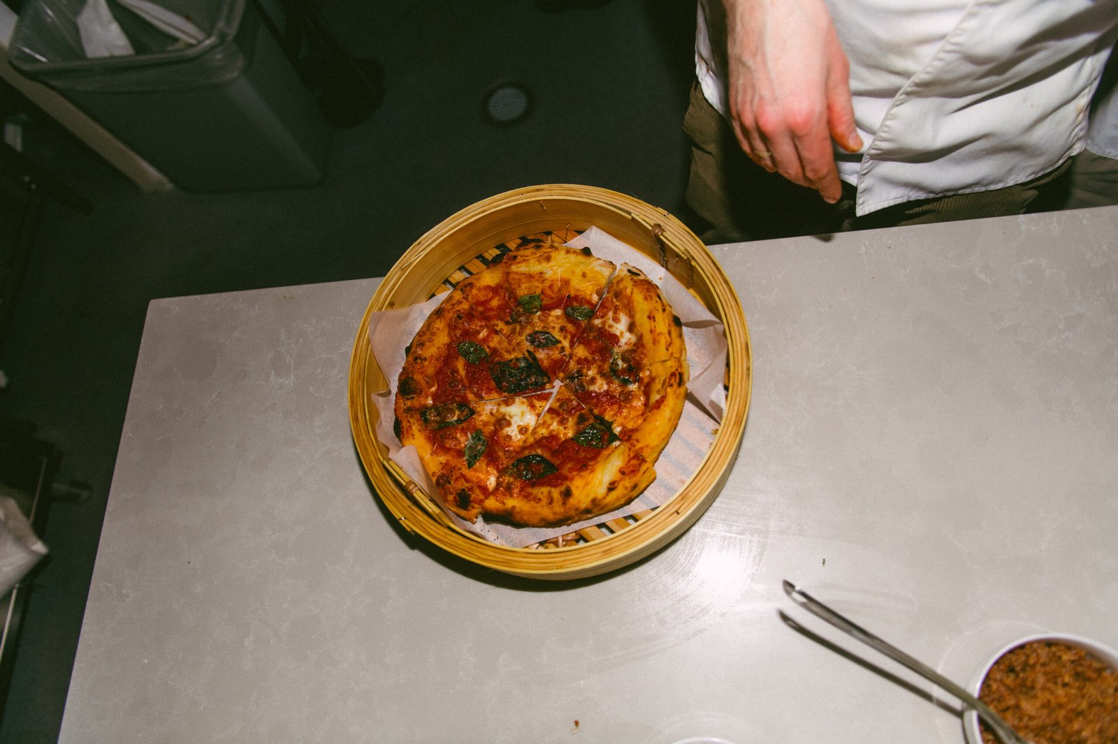 Pizza med tomat, ost og urter servert i bambuskurv