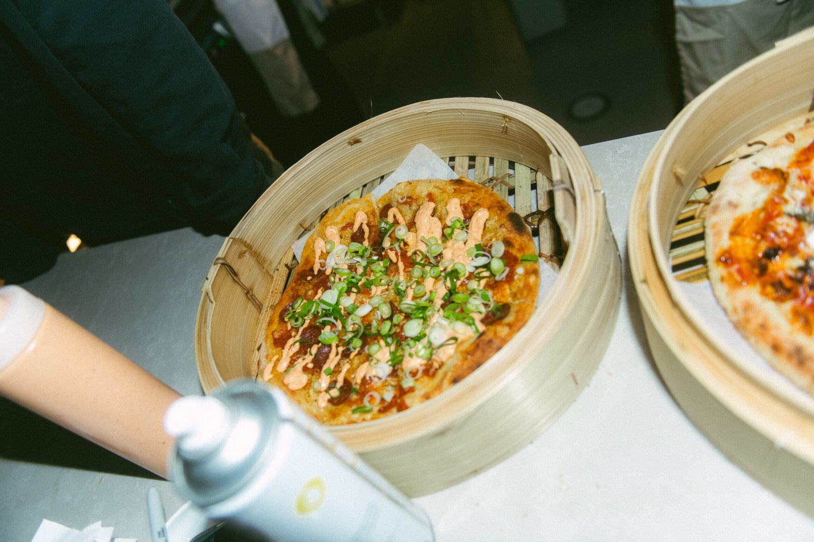 Pizza med vårløk og chilidressing servert i bambuskurv